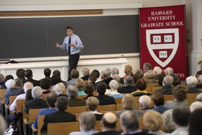 Man lectures in a classroom with GSAS banner on right