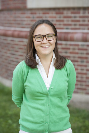 Ashley Skipwith in green shirt in front of brick building