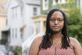 Cherrie Bucknor stands in front of a row of houses