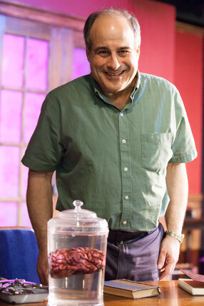 Eric Sirota on Broadway stage for Frankenstein - smiling next to a jar with a brain