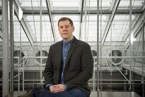 Justin Stern seated in front of glass and metal structure