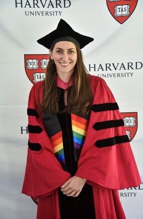 Malinda in graduation regalia with Pride commencement scarf