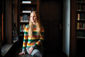 Zoe Jenkin sitting on a dark wooden table with her hand on her lap