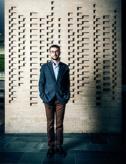 Raphael Koenig in front of a brick wall at Harvard Law School.