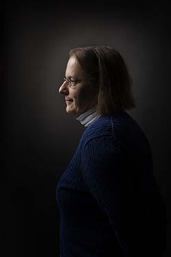 Professor Anne E. Monius in profile with a black background.