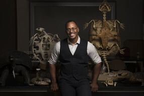 Shane Campbell-Staton poses in front of two animal skeletons