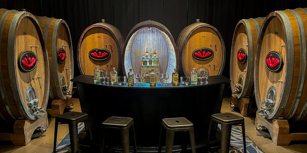 Image of inside a distillery tasting room featuring barrels and various bottles for sampling