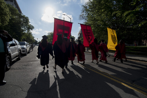 Graduates are silhouetted against a sunny background
