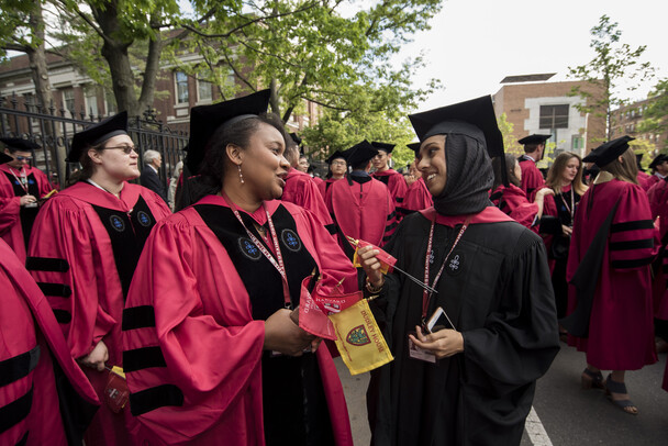 Two students in Commencement robes smile at each other