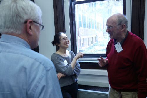 Two male and one female alumni talking and laughing with one another